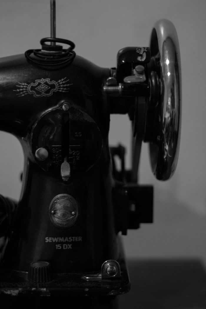 services-04 Close-up of an antique sewing machine displaying intricate details in monochrome.
