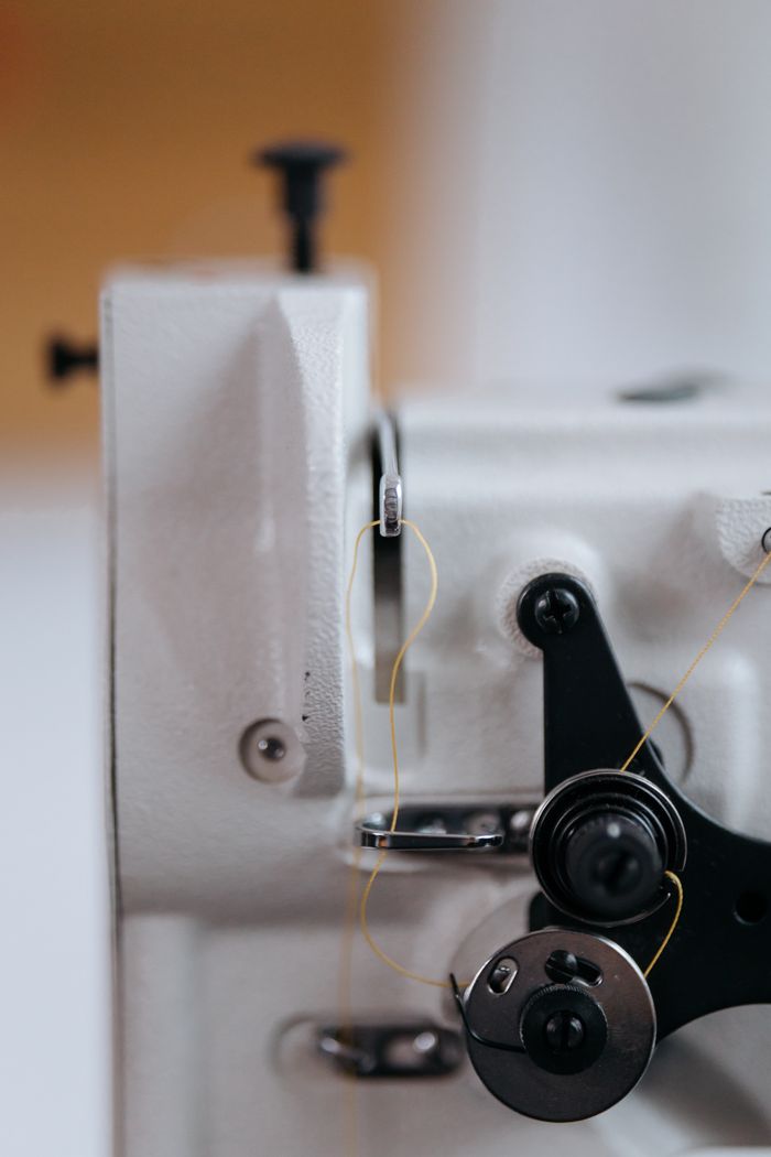 about-us-02 Detailed shot of a vintage sewing machine mechanism with thread and metal components, focusing on the industrial design.