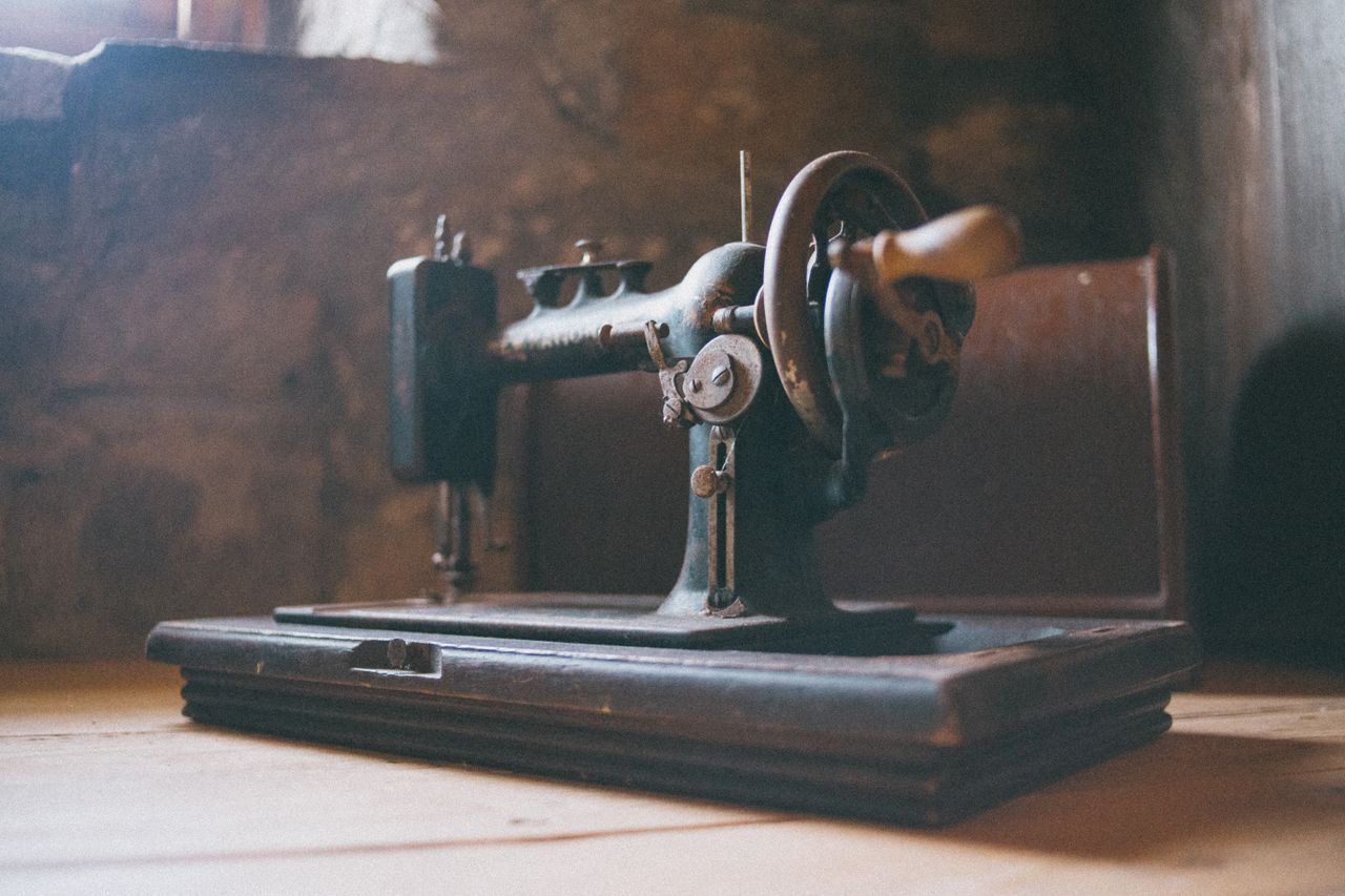 services-01 Close-up of an antique sewing machine highlighting its detailed craftsmanship in a rustic setting.